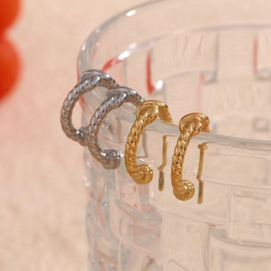Macro shot of twisted spiral earrings in gold and silver finish on textured glass