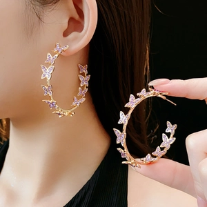 Détails de boucles d'oreilles C dorées avec papillons en cristal violet sur mannequin