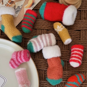 Miniature knitted Christmas socks collection in multiple colors on a woven rattan surface