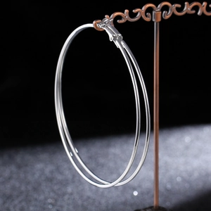 Macro shot of large silver hoop earring hanging on a vintage bronze display stand