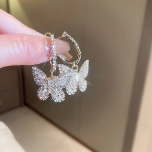 Macro shot of gold butterfly earrings with sparkling cubic zirconia held in hand