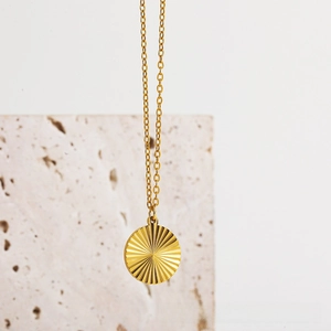 Close-up of a 18k gold plated stainless steel sunburst pendant on a fine link chain