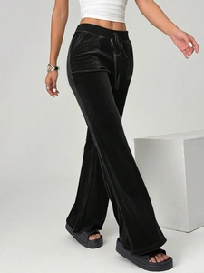 Detailed close-up of high-waist black velvet flared trousers with matching waist tie detail