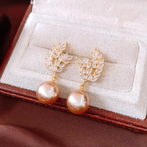Close-up of 18K gold-plated pearl earrings with sparkling marquise zircons on velvet