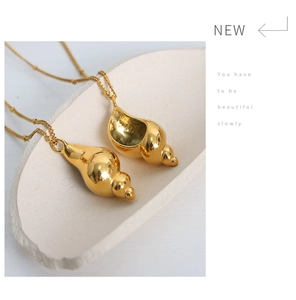 Close-up of golden conch and shell pendants on a fine chain with mirror finish