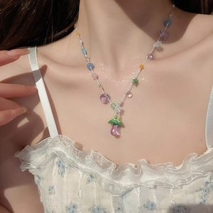 Detail of beaded necklace with a purple mushroom pendant worn on a floral dress