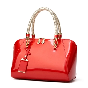 Red patent leather Boston handbag with shell shape and woven handles on white background