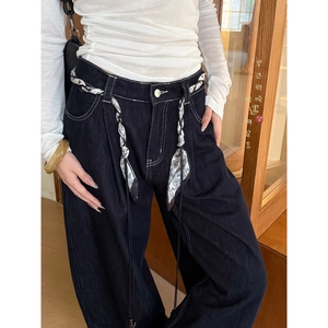 Close-up of wide-leg dark denim jeans with contrast white stitching and paisley scarf belt