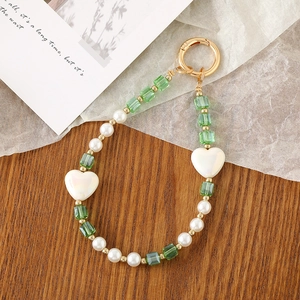 Creative crystal beaded phone strap with green cubes and white hearts on wooden surface