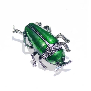 Detailed view of green enamel beetle brooch with sparkling crystal stones and silver legs