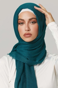 Detail of dark green wrinkle cotton hijab showing fine pleated texture and frayed edges