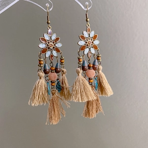 Detail of bohemian floral earrings with wood beads and long khaki cotton tassels