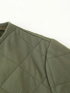 Detailed macro view of military green quilted jacket with diamond stitching and edge piping
