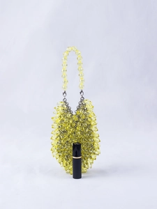 Macro view of handmade yellow crystal drop handbag with metallic bead handle detail