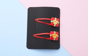 Detail of red glitter Christmas hair clips with 3D gift box on black card display