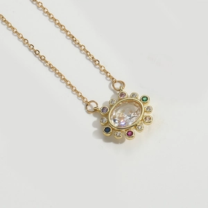Detailed macro view of golden oval pendant necklace with colorful crystals on white background