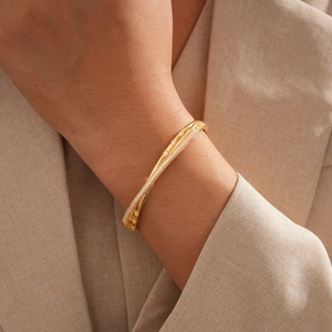 Detail of 18k gold plated double-layer twisted bangle with pavé zircon on a beige blazer