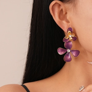 Detail of purple enamel flower earring with gold edges and crystal center on model