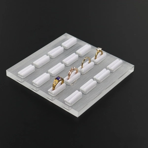Detailed view of clear acrylic jewelry stand with white ring holders on black background