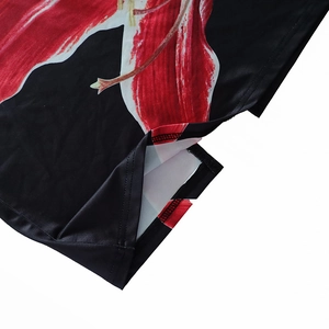 Detail of floral print dress hem showing stitching and glossy black fabric with red flowers