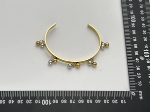 Misurazione dettagliata dei ciondoli a sfera bicolore su un bracciale rigido in acciaio dorato