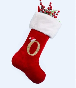 Macro view of red velvet Christmas stocking with gold embroidered letter O and white fur trim