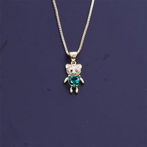 Détail macro du pendentif ours doré avec pierre verte en cœur et zircons brillants