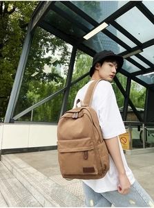 Khaki canvas backpack detail featuring front zipper pocket and adjustable strap