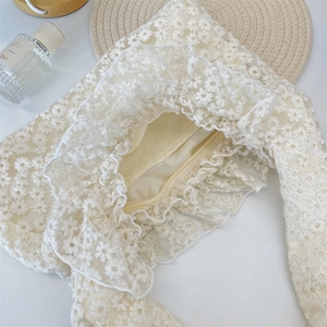 Detailed macro view of daisy lace embroidery and ruffle trim on a cream white handbag
