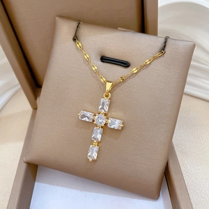 Vue détaillée du collier croix dorée orné de zircons brillants sur un support bijoux