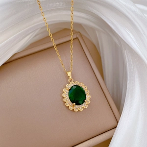 Dettaglio di collana vintage dorata con ciondolo smeraldo ovale e piccoli diamanti