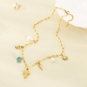 Gold plated ocean themed necklace with starfish shell and pearl charms on sand texture