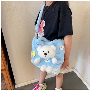 Detail of light blue plush crossbody bag with 3D teddy bear and floral accents on child model