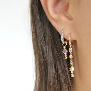 Detail view of gold tassel earrings featuring vibrant purple and pink zircon gemstones