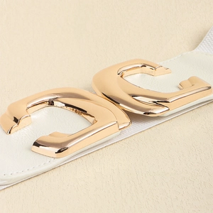 Macro detail of white leather belt with modern gold C-shaped geometric metal buckle