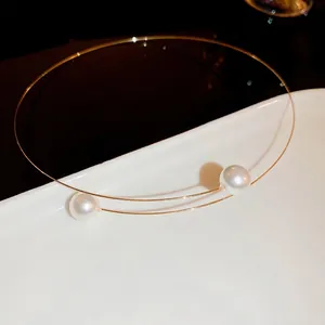 Minimalist gold pearl choker necklace with two white pearls on a metallic round ring