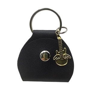Detail of black lychee leather guitar pick holder with silver ring and golden wing charm