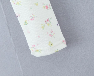 Détail macro du poignet en tricot côtelé à fleurs montrant les coutures et la matière