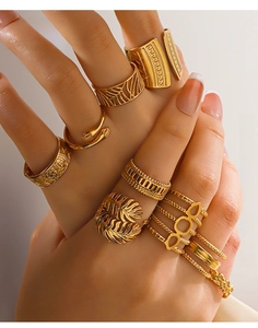 Detailed view of layered 18K gold-plated stainless steel leaf and geometric rings on hand