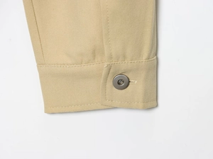 Détail du poignet d'une veste en toile kaki avec bouton métallique et double couture
