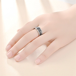 Close-up of retro titanium steel ring with black geometric engraving on a hand
