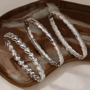 Set of four silver stainless steel bracelets featuring heart chain and textured metal designs