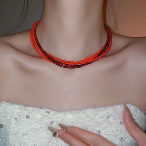 Detail of red multi-layer beaded choker necklace on model neck with elegant gloss