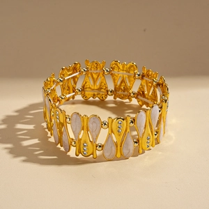 Dettaglio del bracciale elastico dorato con smalto bianco e zirconi in stile vintage
