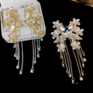 Macro detail of gold flower and butterfly fringe earrings with long crystal tassels
