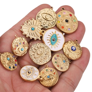 Evil eye pendants in gold finish with colorful enamel and crystals held in palm