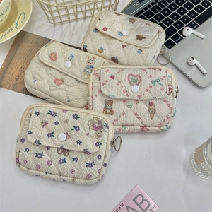 Flat lay of quilted cotton pouches with floral and cartoon prints and metal D-rings