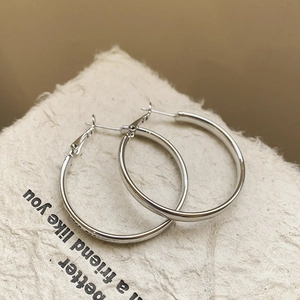 Macro view of minimalist silver hoop earrings with a smooth polished metallic texture