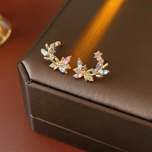 Detail of vintage gold branch earrings with multi-colored crystals on satin surface