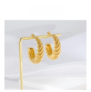 Detail showing 18K gold croissant twisted hoop earrings on a metal display stand